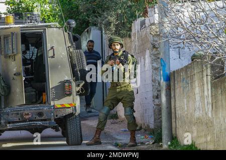 Naplouse, Palestine. 23rd janvier 2023. Les soldats israéliens se tiennent sur la garde tandis que d'autres soldats entourent et cherchent une maison, pendant le raid dans le village de Salem, à l'est de Naplouse, en Cisjordanie occupée. Les forces de l'armée israélienne se sont rompues dans le village de Salem et ont fouillé plusieurs maisons appartenant aux Palestiniens. Crédit : SOPA Images Limited/Alamy Live News Banque D'Images