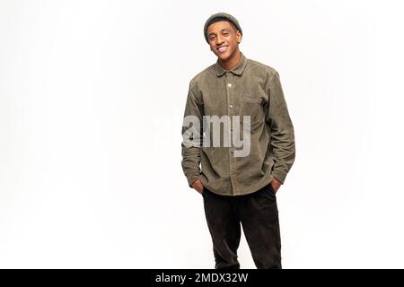Portrait d'un jeune homme beau et heureux satisfait en chemise debout avec les bras aux poches et regardant l'appareil photo avec un sourire crasseux. Studio d'intérieur tourné sur fond blanc Banque D'Images