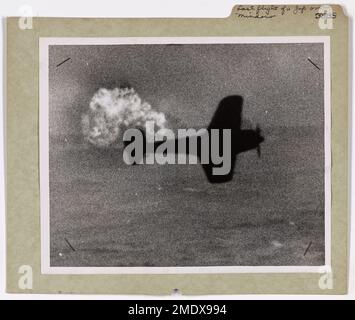 Photographie d'un avion japonais frappé par un débarcadère-embarcation de la Garde côtière. Dernier vol d'un Jap au-dessus de Mindoro. L'éclatement d'une flamme derrière un avion de Jap marque le début de sa plongée dans la mer au large de Mindoro aux Philippines. Attaquant un avion amphibie américain, le bombardier ennemi a été mortellement blessé par une back envoyée par un LST assuré par la Garde côtière. Les tireurs de la Garde côtière ont représenté un autre avion de Jap dans le duel du ciel marin. Banque D'Images