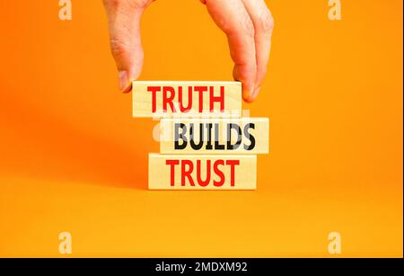 La vérité crée un symbole de confiance. Concept Words Truth construit la confiance sur des blocs de bois sur une belle table orange fond orange. Main d'homme d'affaires. Entreprise Banque D'Images