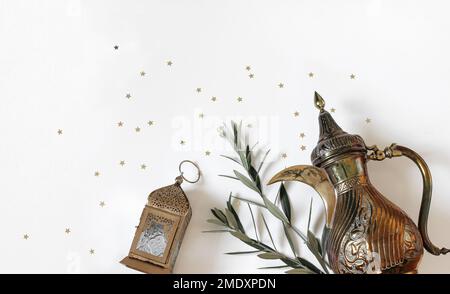 Cadre du Kareem de Ramadan. Botte de dallah arabe, lanterne marocaine ornementale dorée. Branches d'arbre vertes, olve, confetti d'étoiles isolés sur une table blanche Banque D'Images