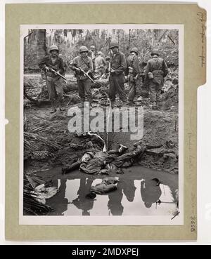 Photographie des troupes américaines se tenant au-dessus des corps des tireurs d'élite japonais tués pendant la bataille de ,. Snipers JAP Snipped aux Philippines. Trois tireurs d'élite de Jap, piégés par les troupes américaines, ont choisi du tirer et de s'enfuir pour les fourrés, pendant la bataille pour l'île Leyte, dans le centre des Philippines. Un photographe de combat de la Garde côtière est arrivé peu de temps après que les tirs de Yankee aient foré les Nips et les ont déposés dans l'eau boueuse d'un cratère à bombe, où ils avaient cherché refuge dans un combat de fusil de course avec les Américains. Banque D'Images