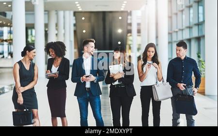 Heureux de vous voir tous ici. un groupe de jeunes gens d'affaires confiants debout dans une rangée à côté l'un de l'autre à l'intérieur du bureau pendant la journée. Banque D'Images