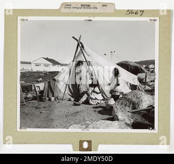 Mission de réapprovisionnement de l'Arctique. Photographiée par un photographe de la Garde côtière du brise-glace WESTWIND, cette scène montre une famille esquimau campée près de la Hudson Bay Co Poste commercial à River Clyde, sur l'île de Baffin, territoire du Nord-Ouest canadien. Ces Esquimaux migrent vers la colonie de la rivière Clyde pour faire du commerce et chasser pendant la courte période de l'été arctique. La rivière Clyde a été le point d'une courte période de rodage du brise-glace DE la Garde côtière, WESTWIND, tout en se présentant avec un groupe de travail de la Marine pour réapprovisionner les stations météorologiques canado-américaines dans l'Arctique. Banque D'Images