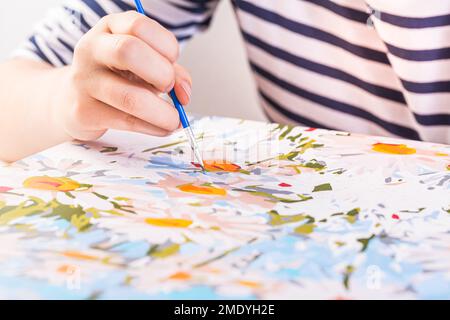 Une main avec dessin au pinceau image de fleurs avec des peintures acryliques sur toile. Concept d'art. Banque D'Images