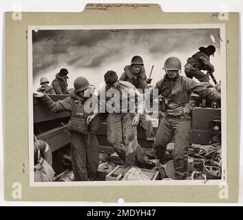 La Garde côtière fait sortir Iwo Jima blessé. Cette image représente une Marine transférée par des gardes-côtes à un bateau d'atterrissage au large de la rive flamboyante d'Iwo Jima. Banque D'Images