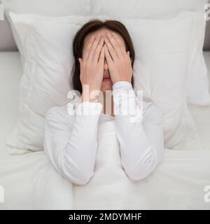 Vue de dessus de la malheureuse brune femme couché dans le lit Banque D'Images