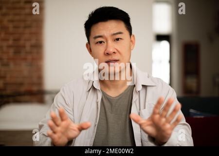 Portrait d'un homme asiatique d'âge moyen regardant la caméra et gestant, communiquant par appel vidéo, vue webcam Banque D'Images