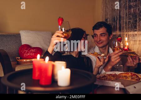 Bonne Saint Valentin couple amoureux de manger de la pizza boire du vin pour dîner romantique célébrant à la maison le soir Banque D'Images