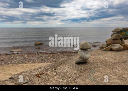 Petite pile de petites pierres sur roche géante au bord de la plage à côté de la mer Baltique Banque D'Images