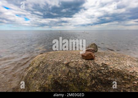 Petite pile de petites pierres sur roche géante au bord de la plage à côté de la mer Baltique Banque D'Images