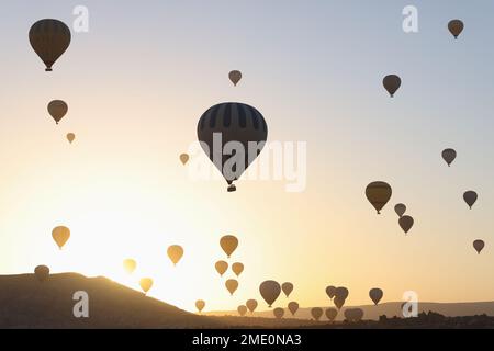 Ciel de coucher de soleil et de nombreux ballons d'air chaud au-dessus des collines. Banque D'Images