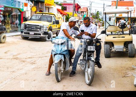 Deux hommes en motocyclette regardent dans le phoneon Isla Holbox île à Quintana Roo Mexique. Banque D'Images