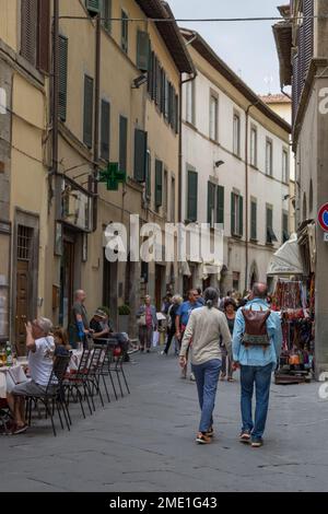 Couple d'âge moyen (homme et femme) tenant les mains marchant vers le bas via Nazionale à Cortona, Toscane, Italie. Banque D'Images