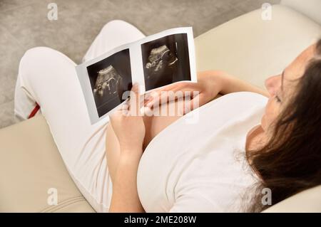Vue en grand angle d'une femme enceinte tout en tenant une image d'un échogramme Banque D'Images