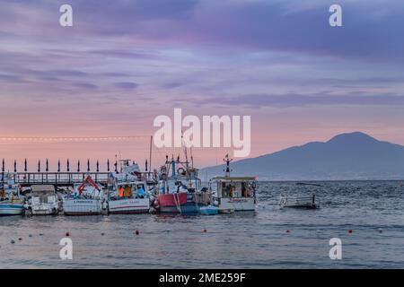 Bateaux amarrés à Marina Grande au coucher du soleil, avec le Vésuve au loin, Sorrento, Campanie, Italie. Banque D'Images