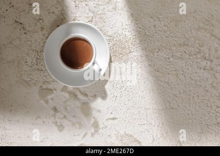 Boisson au cacao dans une tasse blanche sur fond blanc d'argile texturée, vue du dessus Banque D'Images