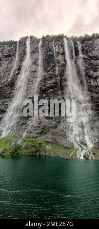 Un plan vertical d'une belle eau mousseuse tombant dans les rochers sous le ciel gris Banque D'Images