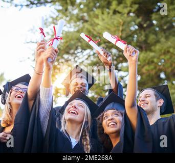 L'aboutissement d'années de travail acharné. un groupe de diplômés qui détiennent leurs diplômes dans l'air. Banque D'Images