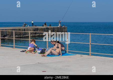 Les baigneurs de soleil vus comme des pêcheurs essayant de pêcher sur les rives de la mer Méditerranée de la ville de Césarée, Israël sur 20 décembre 2022 Banque D'Images