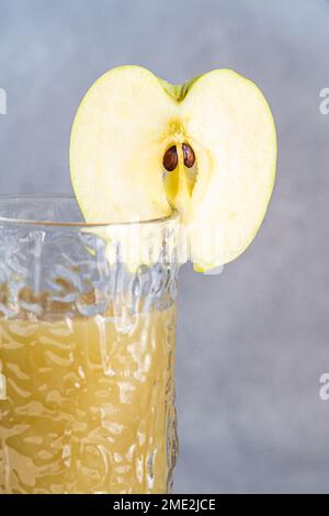 Smoothie aux pommes fraîches servi dans un verre avec des tranches de pomme sur fond de béton Banque D'Images