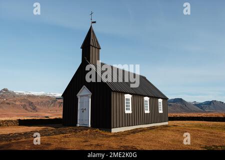 Extérieur de l'église noire Budir située sur une colline herbeuse contre le ciel bleu le jour ensoleillé en Islande Banque D'Images