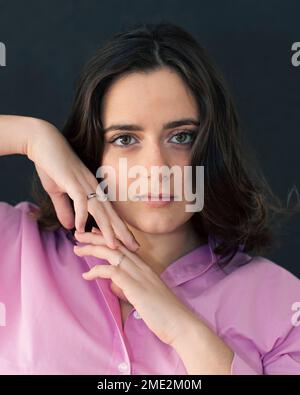 Jeune femme avec des taches de rousseur dans des vêtements décontractés debout sur fond noir regardant l'appareil photo Banque D'Images