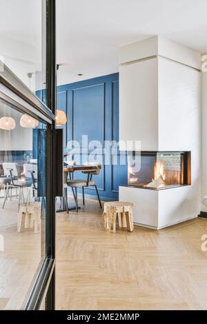 Porte vitrée ouverte menant à une salle à manger moderne avec cheminée en verre dans la journée à la maison Banque D'Images