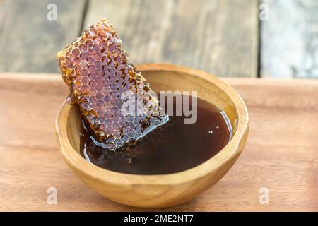 Un morceau de nid d'abeilles assis dans un bol en bois de miel biologique Banque D'Images