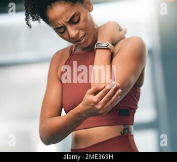 Coude, douleur et forme physique avec une femme noire de sport dans la salle de gym avec une plaie articulaire d'une séance d'exercice. Blessure, formation et santé avec un jeune Banque D'Images