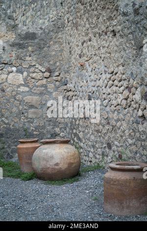 Mur en pierre et pots d'argile creusés dans l'ancienne ville romaine de Pompéi, site archéologique classé au patrimoine mondial de l'UNESCO à Pompéi, Campanie, Italie. Banque D'Images