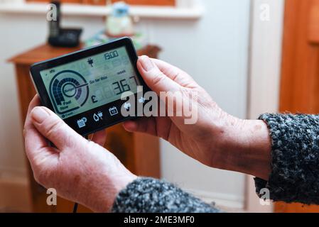 Une femme âgée regarde le compteur intelligent pour établir un budget pour les factures d'énergie pour le ménage Banque D'Images