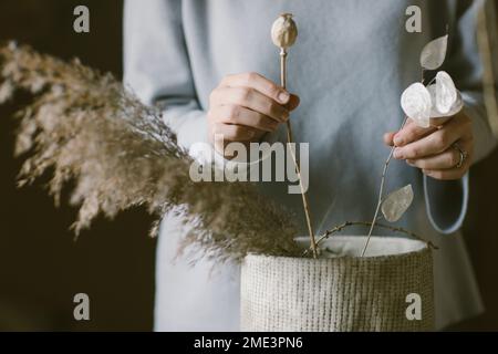 Femme organisant des fleurs et des herbes dans un vase Banque D'Images