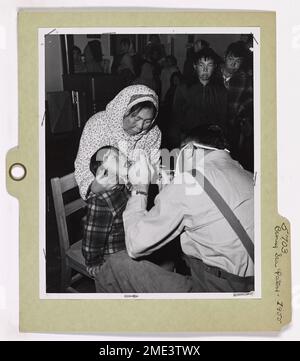 Béring Sea Patrol - Cutter de la Garde côtière KLAMATH, Savonga, St. Lawrence Island, Alaska (4 de 10). Amy Aukutok, enfant esquimau de Savonga, St. L'île Lawrence, qui est détenue par sa mère, est tenue de s'ouvrir à l'ensemble du lieutenant Fred Abramson, dentiste du Service de santé publique, du Cutter KLAMATH de la Garde côtière. Amy a été l'un des nombreux autochtones examinés dans la maison d'école du village avant que les patients reçoivent le traitement nécessaire dans le cabinet dentaire bien équipé à bord du cutter. Au cours d'une croisière de quatre mois, lors de sa première patrouille de la mer de Béring, le KLAMATH a transporté des services dentaires et médicaux aux autochtones dans les régions éloignées Banque D'Images