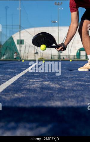 Main d'un jeune homme avec une raquette jouant au paddle-tennis sur un terrain de sport Banque D'Images