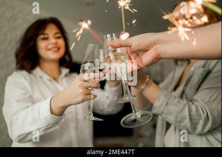 Des amis heureux qui apprécient avec des verres de champagne et des sparkers à la maison Banque D'Images