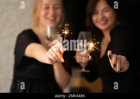 Des amis heureux fêtant Noël avec des verres à champagne et des sparkers Banque D'Images