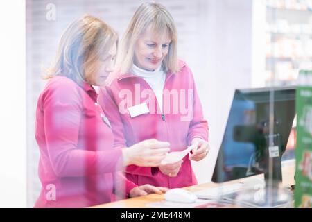 Pharmacien souriant discutant de la prescription avec un collègue vu à travers le verre Banque D'Images