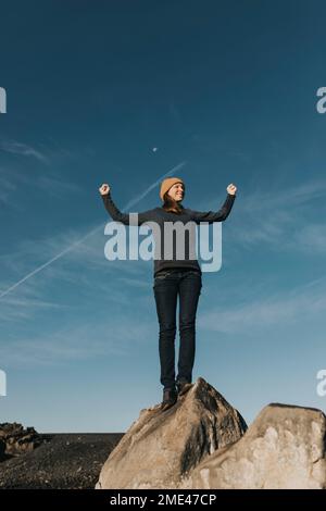 Femme flexion de muscles debout sur le rocher à la plage de Janubio, Lanzarote, îles Canaries, Espagne Banque D'Images