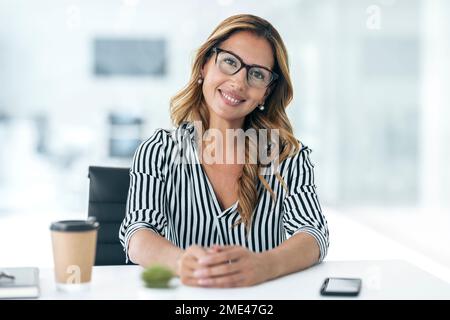 Bonne femme d'affaires mûre portant des lunettes de vue assise au bureau Banque D'Images