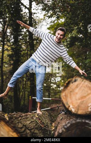 Homme mûr heureux avec les bras débordés équilibre sur le log Banque D'Images