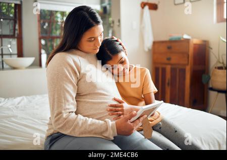 La mère enceinte et l'enfant regardent ensemble un cadre photo dans la chambre de leur maison moderne. Triste, émotionnel et mère avec la grossesse la tenant Banque D'Images