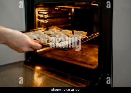 Mains de mère mettant des croissants au four à la maison Banque D'Images