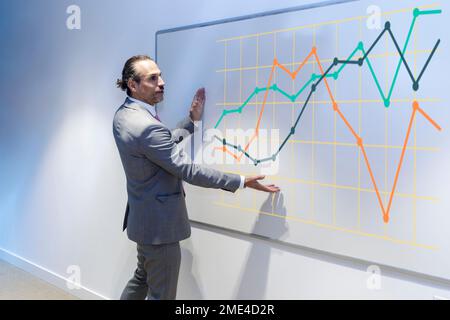 Homme d'affaires expliquant le graphique sur le tableau blanc dans la salle de conférence Banque D'Images