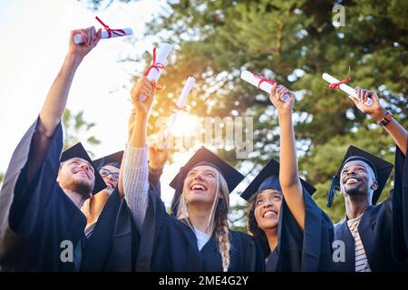 Prenez un moment pour vous réjouir de la réussite de votre diplôme. un groupe de diplômés qui détiennent leurs diplômes dans l'air. Banque D'Images