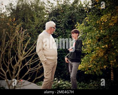 Grand-père et petit-fils parlant dans un garçon de jardin portant une fourche de jardin Banque D'Images