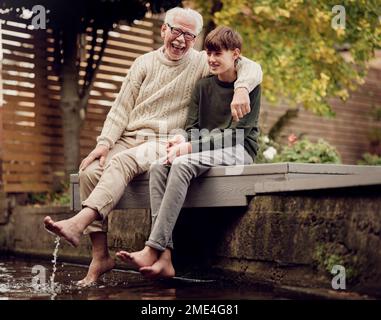 Petit-fils et grand-père assis dans le jardin et parlant ensemble Banque D'Images