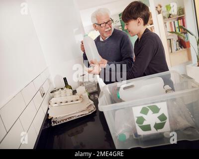 Grand-père et petit-fils mettant les déchets séparés dans une boîte de recyclage Banque D'Images