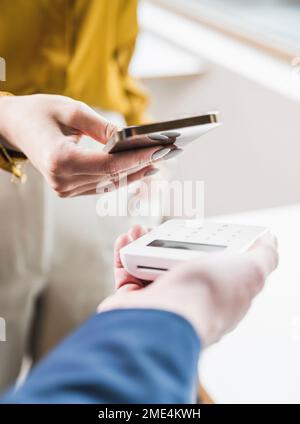 Main de la jeune femme d'affaires payant par téléphone intelligent sur lecteur de carte de crédit Banque D'Images