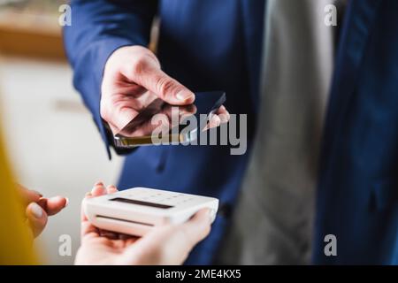 Main d'un jeune homme d'affaires payant par smartphone Banque D'Images